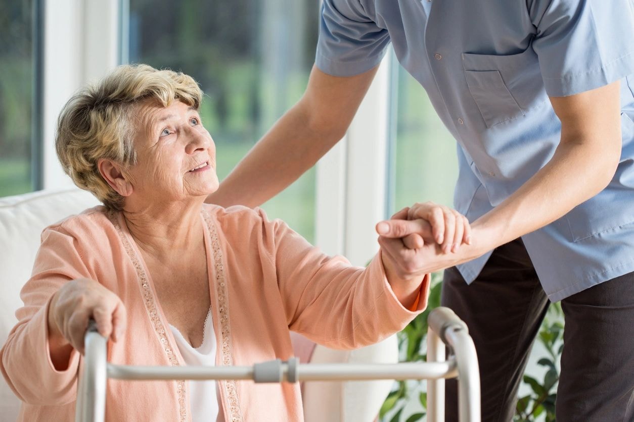 Indian caregiver holding elderly woman's hands